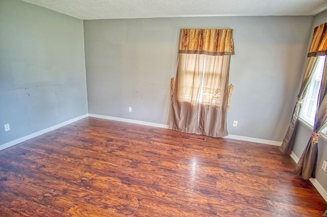 unfurnished room featuring a textured ceiling and dark hardwood / wood-style floors