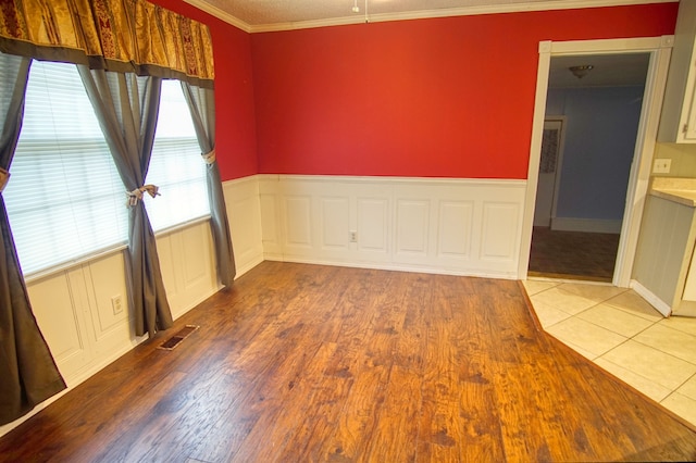 spare room featuring ornamental molding and light hardwood / wood-style flooring