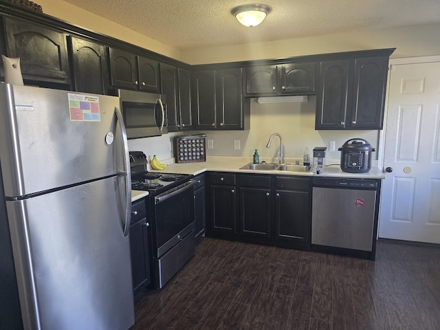 kitchen featuring appliances with stainless steel finishes, a textured ceiling, sink, and dark wood-type flooring