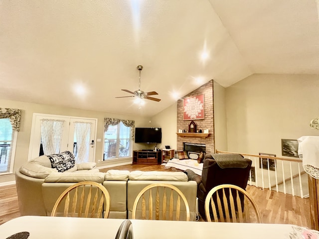 living room with ceiling fan, a fireplace, light hardwood / wood-style floors, and vaulted ceiling