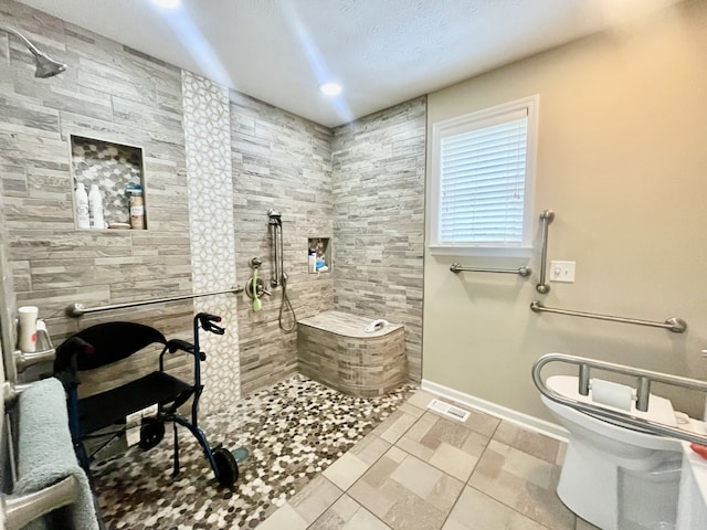 bathroom featuring toilet, tiled shower, and a textured ceiling