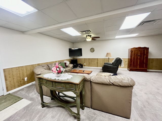 carpeted living room featuring a paneled ceiling, ceiling fan, and wooden walls