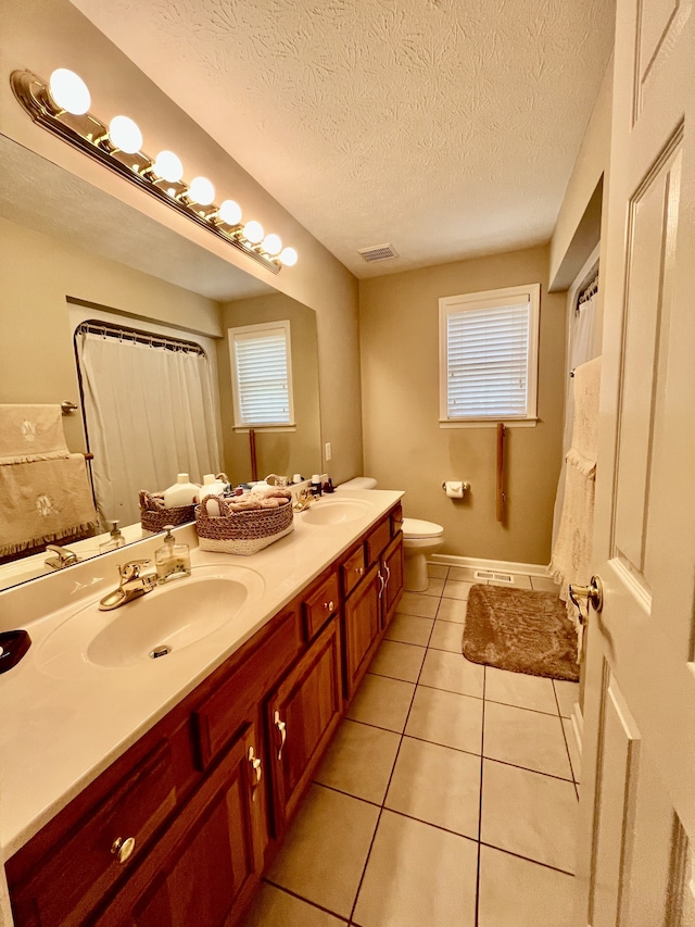 bathroom with vanity, toilet, a wealth of natural light, and a textured ceiling