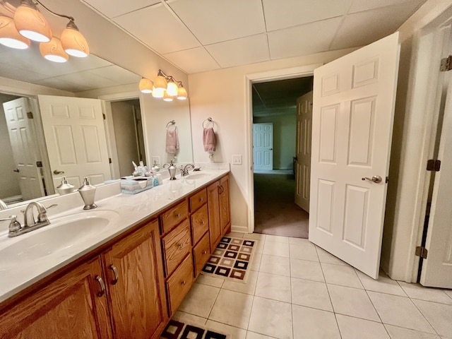 bathroom with tile patterned flooring, vanity, a notable chandelier, and a drop ceiling