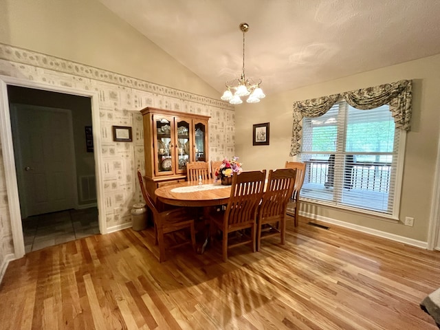 dining area featuring vaulted ceiling, hardwood / wood-style flooring, and a chandelier