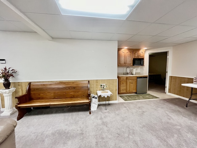 unfurnished room with light carpet, wooden walls, and a drop ceiling