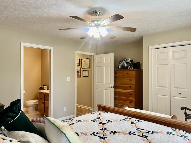 bedroom with a textured ceiling, ceiling fan, a closet, and connected bathroom