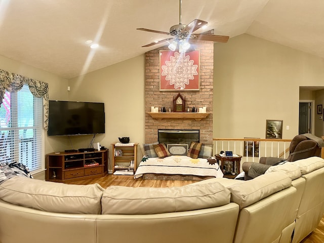 living room with wood-type flooring, ceiling fan, a brick fireplace, and vaulted ceiling