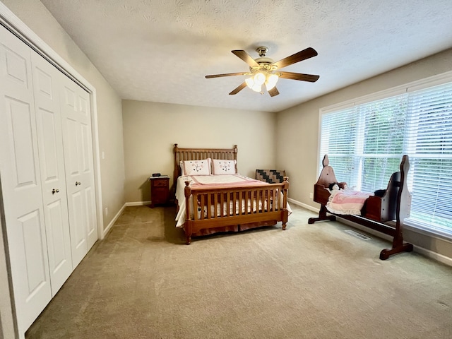 carpeted bedroom with a textured ceiling, ceiling fan, and a closet