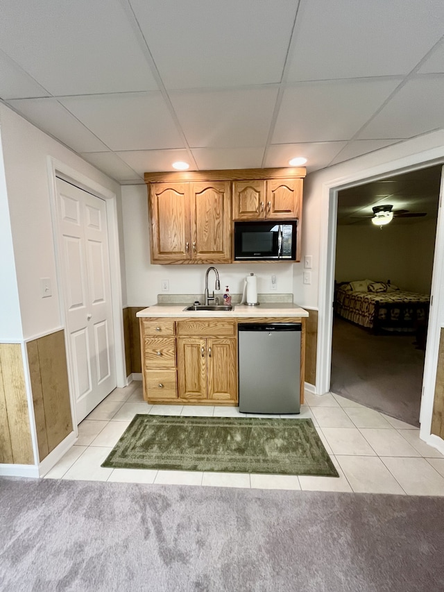 kitchen with light tile patterned floors, a paneled ceiling, stainless steel dishwasher, and sink