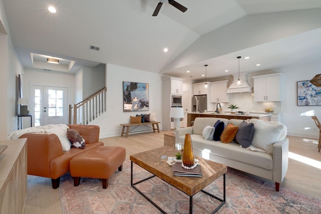 living room featuring ceiling fan, light wood-type flooring, sink, and vaulted ceiling