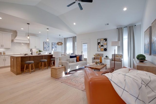 living room featuring ceiling fan, light hardwood / wood-style floors, and lofted ceiling