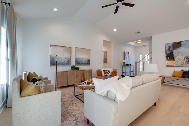 living room with ceiling fan, light hardwood / wood-style floors, and vaulted ceiling