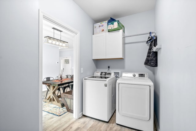 clothes washing area with light hardwood / wood-style floors, cabinets, and washing machine and dryer