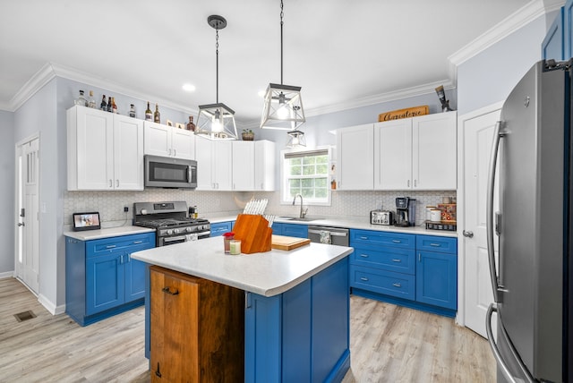 kitchen featuring blue cabinets, a center island, decorative light fixtures, and stainless steel appliances