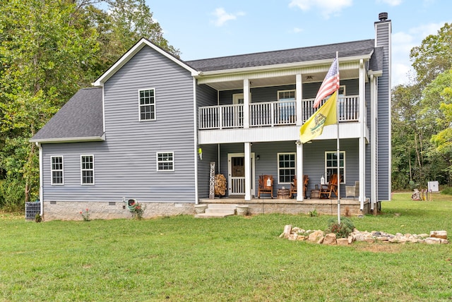 rear view of house with a balcony and a lawn