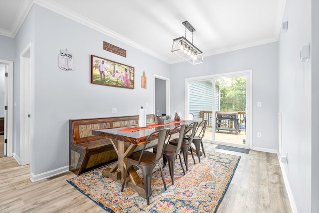 dining space with light wood-type flooring, an inviting chandelier, and crown molding