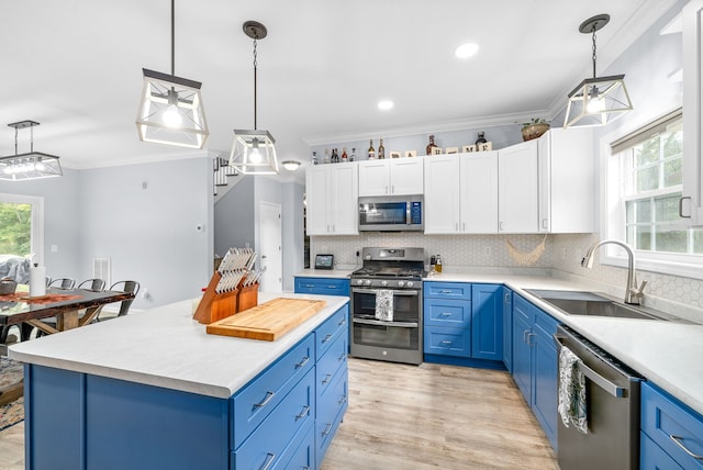 kitchen with blue cabinets, hanging light fixtures, stainless steel appliances, sink, and white cabinetry