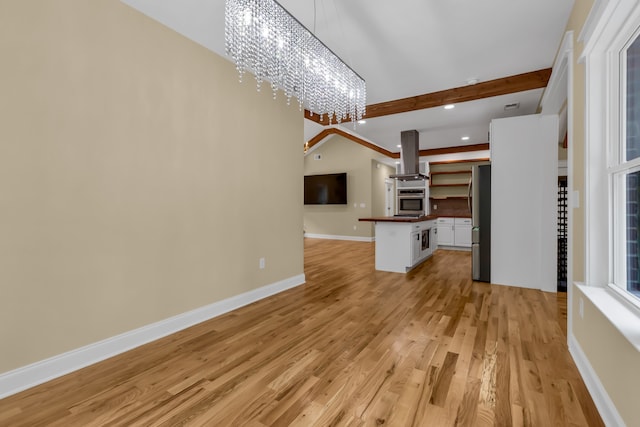 unfurnished living room with light wood-type flooring, a chandelier, and vaulted ceiling