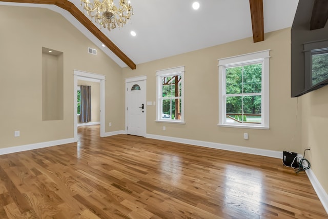 unfurnished living room featuring lofted ceiling with beams, hardwood / wood-style flooring, and a notable chandelier