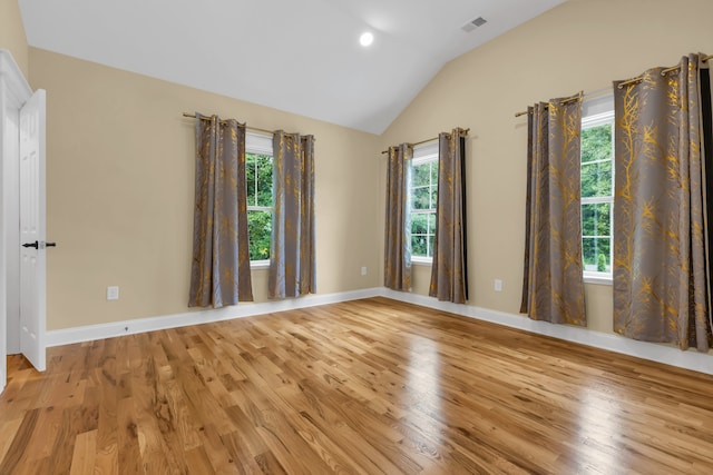 empty room with lofted ceiling, plenty of natural light, and light hardwood / wood-style flooring