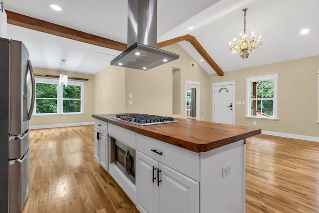 kitchen with a kitchen island, wood counters, island exhaust hood, stainless steel appliances, and white cabinetry