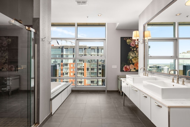 bathroom with tile patterned flooring, independent shower and bath, plenty of natural light, and vanity