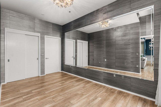 empty room featuring light hardwood / wood-style flooring and a chandelier