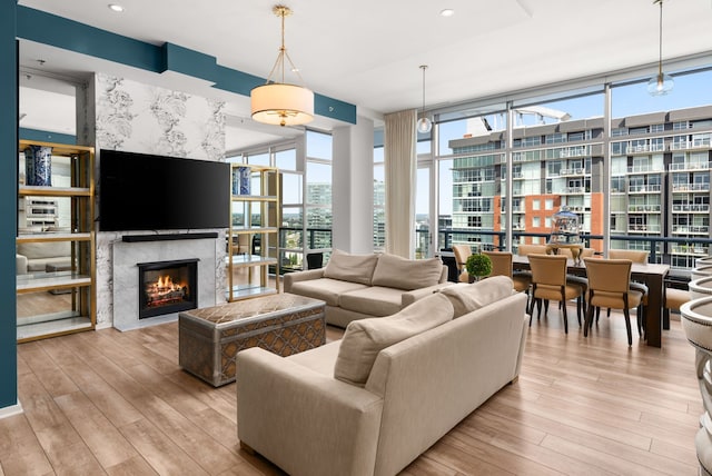 living room with light wood-type flooring, a premium fireplace, plenty of natural light, and expansive windows