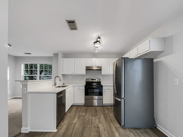 kitchen with dark hardwood / wood-style floors, stainless steel appliances, sink, kitchen peninsula, and white cabinets