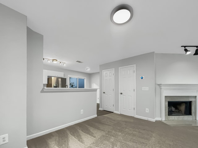 unfurnished living room with rail lighting and a fireplace