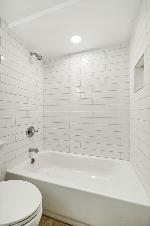 bathroom featuring tiled shower / bath combo, toilet, and tile patterned flooring