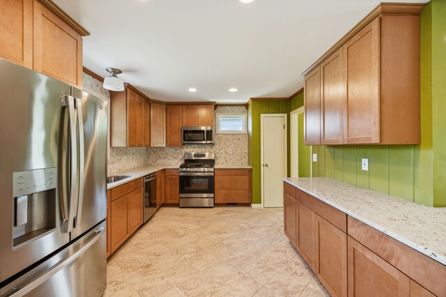 kitchen featuring tasteful backsplash, sink, stainless steel appliances, and light stone countertops