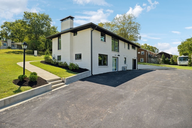 view of side of property featuring a yard and central AC unit