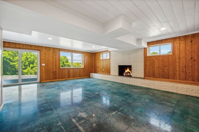 unfurnished living room featuring ornamental molding, wooden walls, and a fireplace