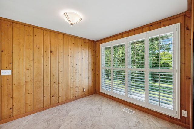 empty room featuring plenty of natural light and wood walls