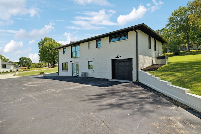 view of side of home with a garage, a lawn, and central AC