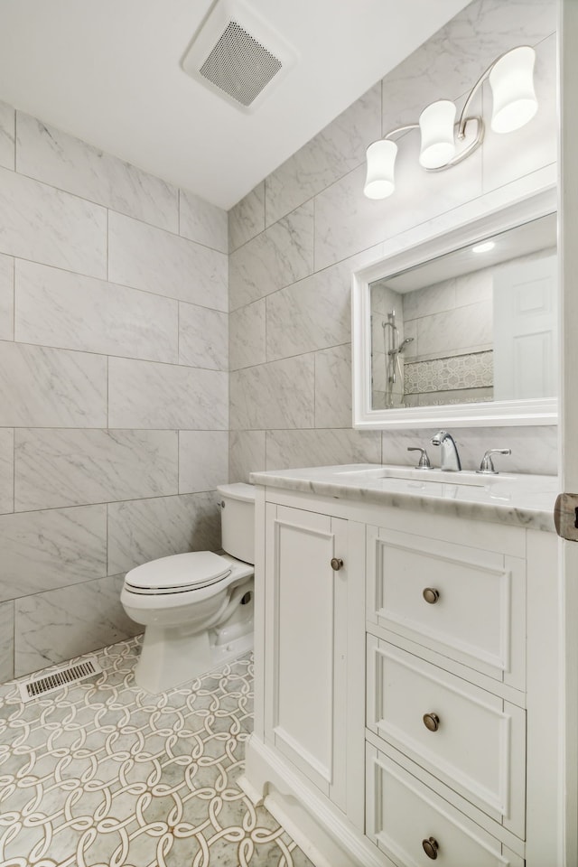 bathroom featuring tile walls, tile patterned flooring, toilet, and vanity