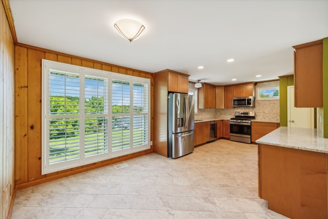 kitchen featuring a wealth of natural light, stainless steel appliances, light stone counters, and tasteful backsplash