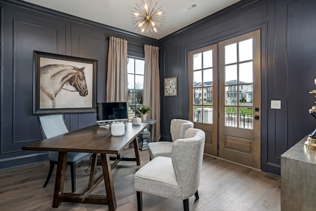 dining area featuring french doors, hardwood / wood-style floors, a notable chandelier, and ornamental molding