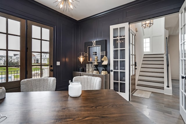 dining space with hardwood / wood-style flooring, ornamental molding, an inviting chandelier, and french doors