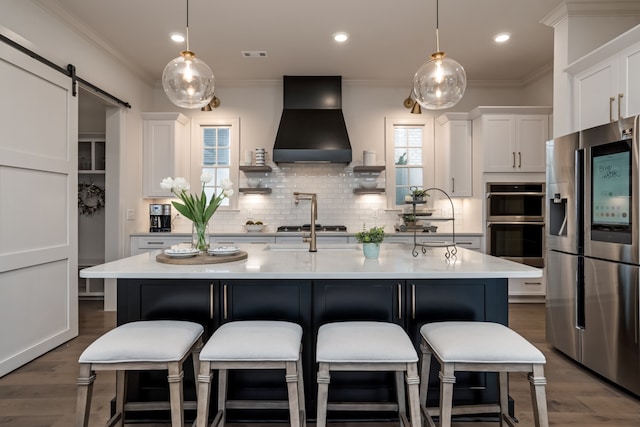 kitchen featuring white cabinets, custom range hood, a barn door, stainless steel appliances, and dark hardwood / wood-style floors