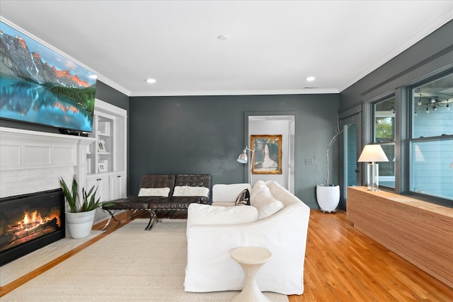 living room featuring a brick fireplace, hardwood / wood-style flooring, and crown molding