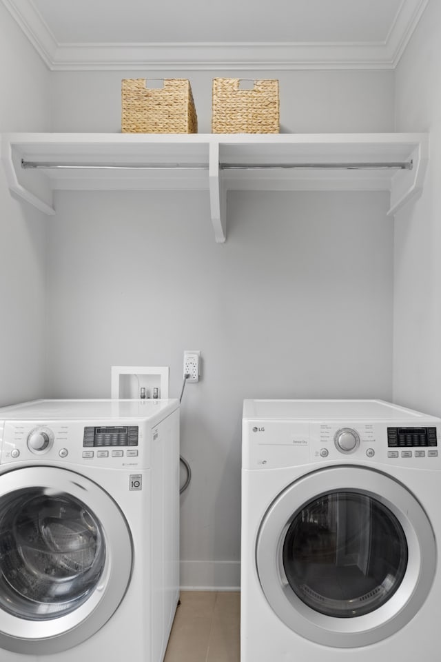 clothes washing area featuring tile patterned flooring, washer and dryer, and crown molding