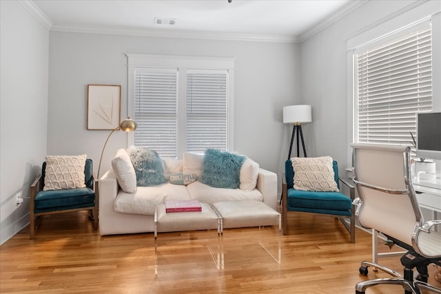 living area featuring a healthy amount of sunlight, wood-type flooring, and crown molding