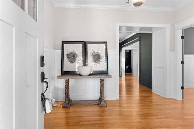 hallway with light hardwood / wood-style flooring and ornamental molding