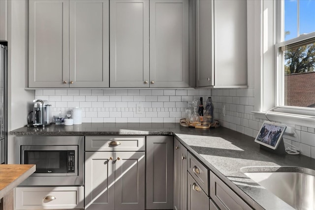 1227 Mcgavock Pike, Nashville, TN 37216 - kitchen with stainless steel microwave, backsplash, gray cabinets, and dark countertops