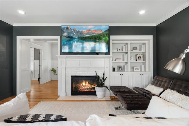 living room featuring crown molding, a fireplace, and light hardwood / wood-style flooring