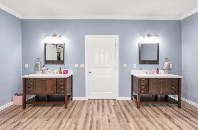 bathroom featuring a sink, baseboards, two vanities, and wood finished floors