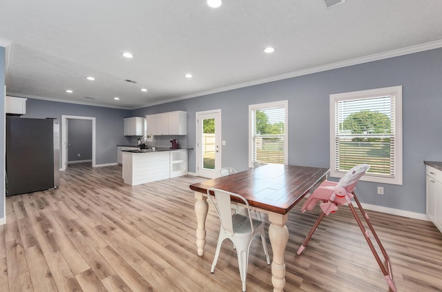 dining area with light wood-style flooring, baseboards, and ornamental molding